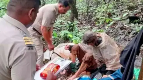 BBC Lalita Kayi being assisted by police officers in the forests of Maharashtra state. 