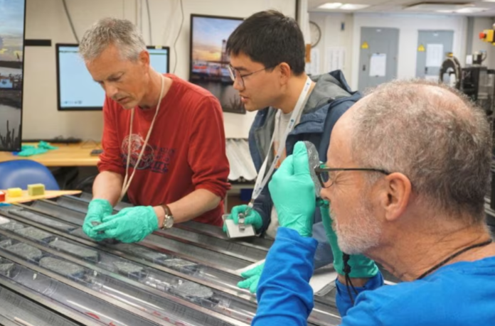 geologist johan lissenberg from cardiff university and two colleagues analyze rock from earth s mantle drilled from the atlantic seabed aboard the ocean drilling vessel joides resolution above atlantis massif in the atlantic ocean in this handout photograph taken on may 4 2023 and released on august 8 2024 scientists are analyzing the mantle rocks to establish their mineralogy and chemical makeup photo reuters