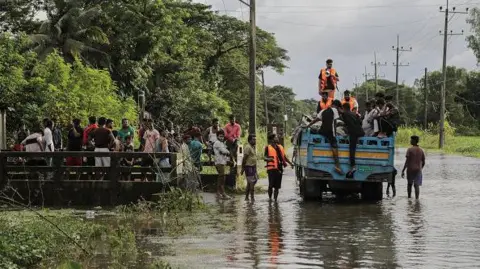 Getty Images Volunteers try to make a que before delivering relief food package in Feni, Chittagong, Bangladesh, August 26, 2024.