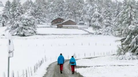 JOHANN GRODER/APA/EXPA/AFP Hikers walk through the snow-covered landscape at the Kalser Ködnitztal valley in Kals am Grossglockner, Tyrol, Austria, on September 13, 2024