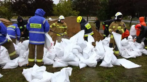 EPA Firefighters build barriers with sandbags against flood water, near the river Biala Glucholaska, in Glucholazy, southwestern Poland, 14 September 2024. 