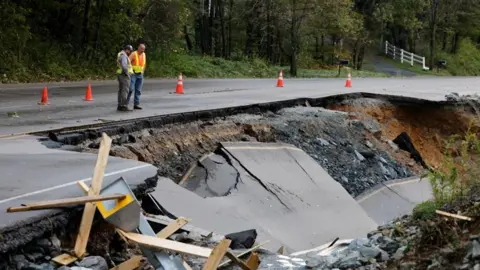 Reuters Workers survey a large section of Highway 105 that washed away because of flood waters during Tropical Storm Helene