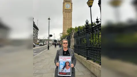 Mandy Damari  A picture of Mandy Damari holding a poster calling for her daughter to be brought home