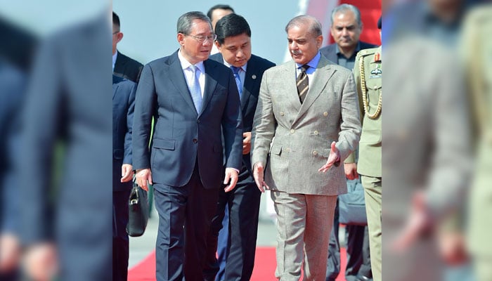 Prime Minister Shehbaz Sharif (right) walks with his Chinese counterpart Li Qiang as he arrives at Nur Khan Airbase in Rawalpindi, on October 14, 2024. — PMO