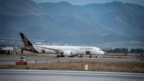 Getty Images A Vistara Airlines passenger plane sits at the airport There are mountains in the background