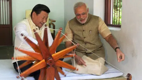 Prime Minister's Office Modi and Xi seen sitting on flat white cushion as they work and Indian spinning wheel at the Sabarmati Ashram in Gujarat in 2014