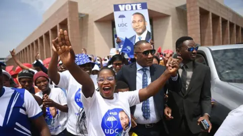 AFP A smiling UDC supporter holds her hands in the air as she greets party leader Duma Boko.