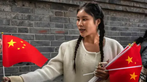 Getty Images A woman sells Chinese flags in a historic neighbourhood of Beijing ahead of National Day celebrations.