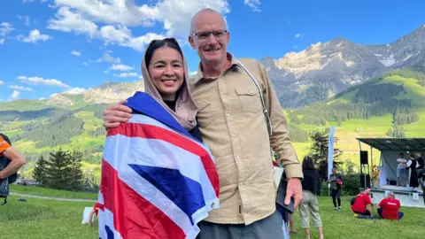 Fatima Painda Fatima Painda draped in a Union flag and standing next to her coach, Paul Harkins. There are mountains in the background