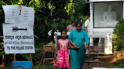 Getty Images A woman walks with her daughter as she leaves a polling station after casting her vote on the day of the parliamentary election, in Colombo, Sri Lanka, November 14, 2024.