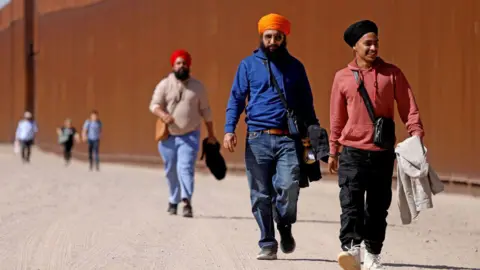 Getty Images Immigrants from India walk along the border wall to turn themselves over to US Border Patrol agents on the US-Mexico border, 11 May 2023 in San Luis Río Colorado, Sonora.