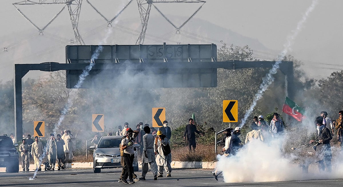 Members of jailed former prime minister Imran Khan´s Pakistan Tehreek-e-Insaf (PTI) party attempt to throw back teargas shells fired by riot policemen as they protest during a march to Islamabad in Hasan Abdal in Punjab province on November 25, 2024. — AFP