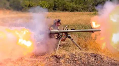 Facebook James Scott Rhys Anderson kneeling down firing a rocket from a launcher with fire on either side.