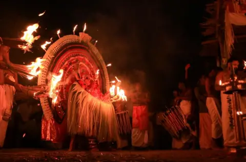 KK Gopalakrishnan A performer is surrounded by people holding flame-lit torches