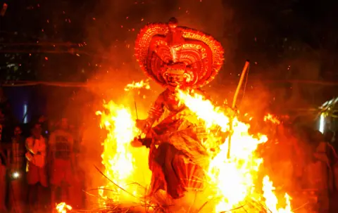 KK Gopalakrishnan A man with a large headdress performing with fire, carrying burning torches