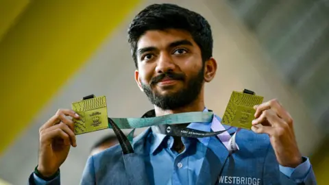 Getty Images Gold medalist grandmaster Dommaraju Gukesh, shows his medals upon his arrival at the Chennai International Airport in Chennai on September 24, 2024, after his win at the 45th FIDE Chess Olympiad Budapest 2024. (