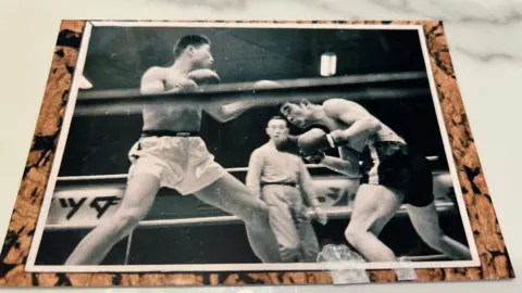 A black-and-white photograph of two boxers fighting in a ring