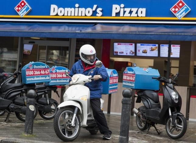 a staff member delivers take away pizzas to customers at a domino 039 s pizza store photo reuters