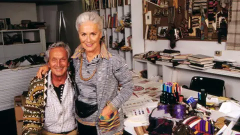 Getty Images Italian fashion designer Ottavio Missoni and his wife Rosita Jelmini in the office of their fashion house in Sumirago. Both have short grey hair and wear signature Missoni knitwear. 