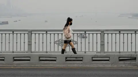 Getty Images A woman walks on the Wuhan bridge over the Yangtze river in Wuhan, in China's central Hubei province on December 22, 2024