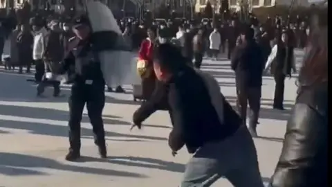 A protester hurling an object at a police officer in a Pucheng demonstration. Grab from video on X