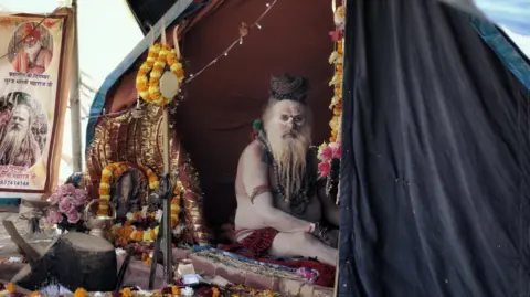 Ankit Srinivas An ash-smeared Hindu holy man sits in a tent at the Kumbh Mela festival in Prayagraj in January 2025