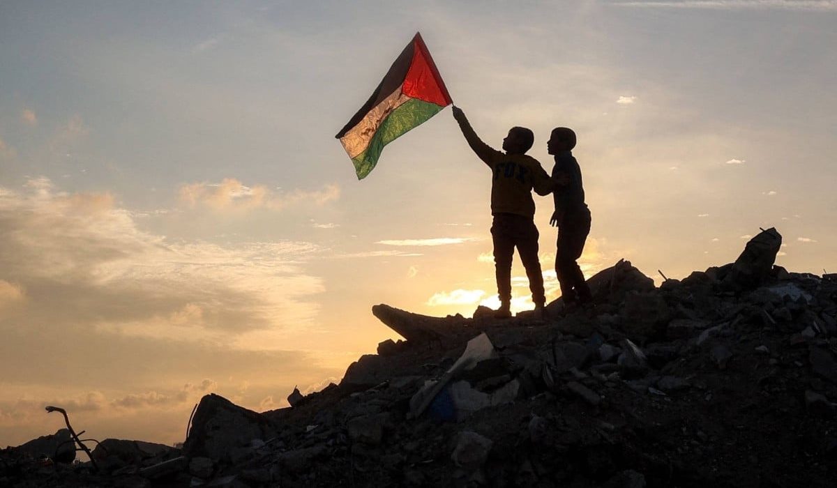 a boy runs with a palestinian flag atop a mound of rubble at a camp in bureij central gaza strip on friday photo afp