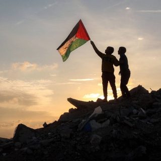 a boy runs with a palestinian flag atop a mound of rubble at a camp in bureij central gaza strip on friday photo afp