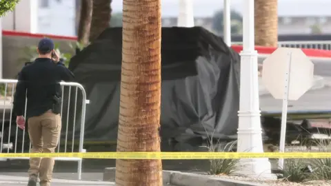 Reuters Officer walks near the remains of a black-tarp covered Tesla Cybertruck that burned at the entrance of Trump Tower, in Las Vegas