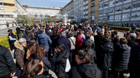 Reuters Dozens of people gather outside a statue of late Pope John Paul II outside the Gemelli Hospital where Pope Francis is receiving treatment