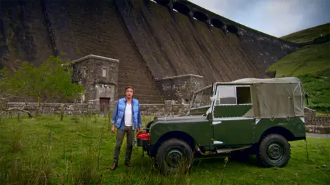 Former Top Gear presenter Richard Hammond with a green Land Rover in front of Claerwen Dam 