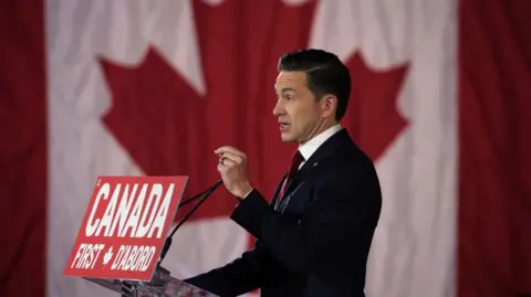 Getty Images Pierre Poilievre standing before a Canadian flag at his Canada First rally in Ottawa in February 