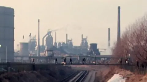 Archive photo shows a railway track leading to a large industrial plant.