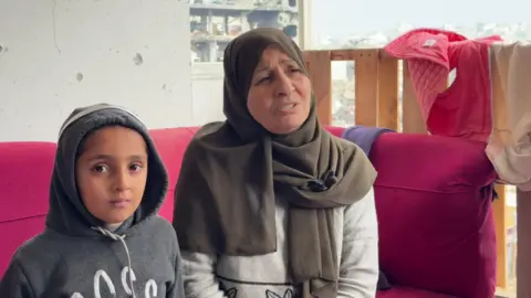 Laila sits on a pink sofa with a young girl