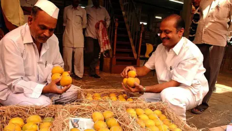 Getty Images The photo gives a view of the traders and buyers for Alphonso Mango, wearing traditional caps at a market in Mumbai, Maharashtra, India. 