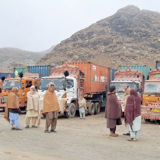 people stand next to parked trucks loaded with supplies at the torkham border crossing following a clash between pakistan and afghanistan photo reuters