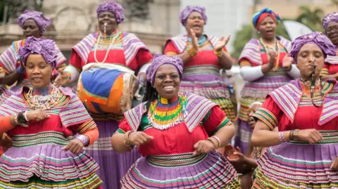 AFP Women in traditional, multi-coloured Basotho outfits sing and dance 