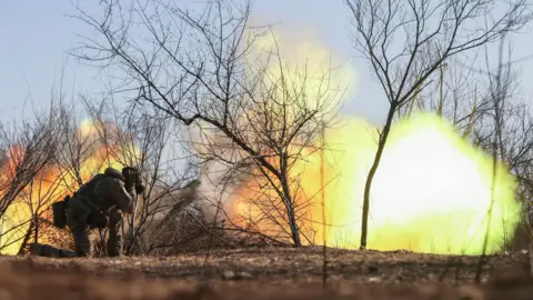 EPA A Ukrainian soldier covers his ears as a howitzer fires in the Zaporizhzhia region of Ukraine